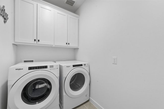 Laundry area with light tile patterned floors, washing machine and dryer, and cabinets | Image 12
