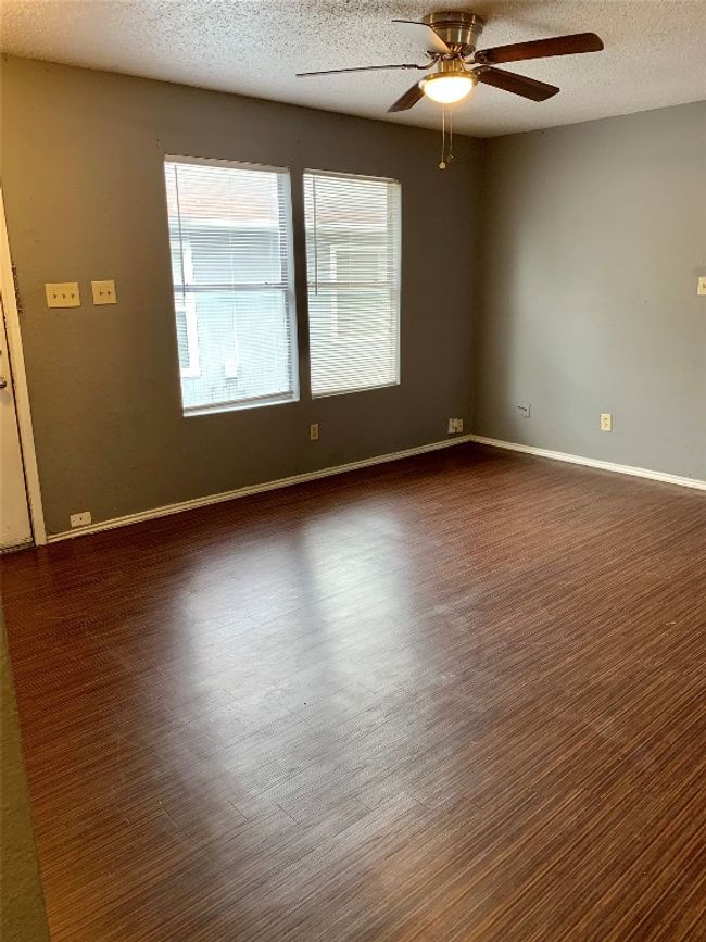 Unfurnished room featuring dark wood-type flooring, baseboards, a textured ceiling, and ceiling fan | Image 7