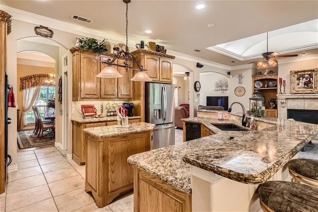 Kitchen with a spacious island, visible vents, arched walkways, stainless steel fridge, and a ceiling fan | Image 11
