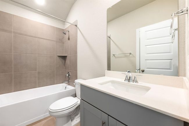 Secondary bathroom features Quartz countertops and cabinets, neutral paint, shower/tub combo with tile surround, large mirror, tile floors, sleek fixtures and modern finishes, plenty of space to accommodate any visiting family or guests. | Image 14