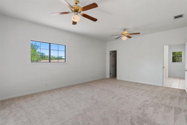 Empty room featuring a wealth of natural light, light colored carpet, ceiling fan, and visible vents | Image 26
