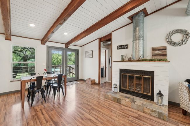 Dining room with a glass covered fireplace, wood finished floors, baseboards, wood ceiling, and french doors | Image 13