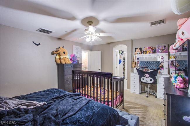 Bedroom with light colored carpet, arched walkways, and a ceiling fan | Image 17