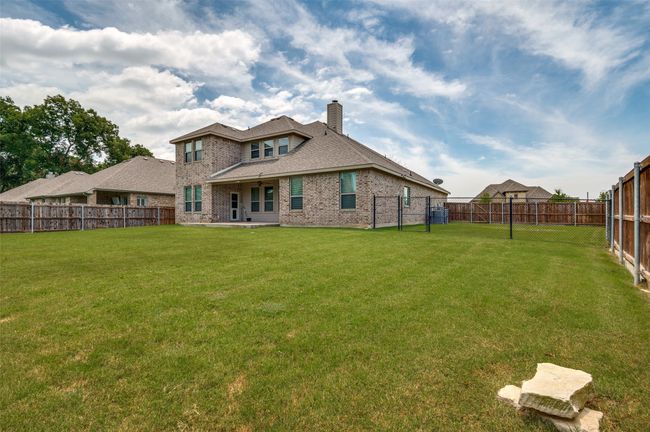 Rear view of house featuring brick siding, a fenced backyard, a chimney, and roof with shingles | Image 27
