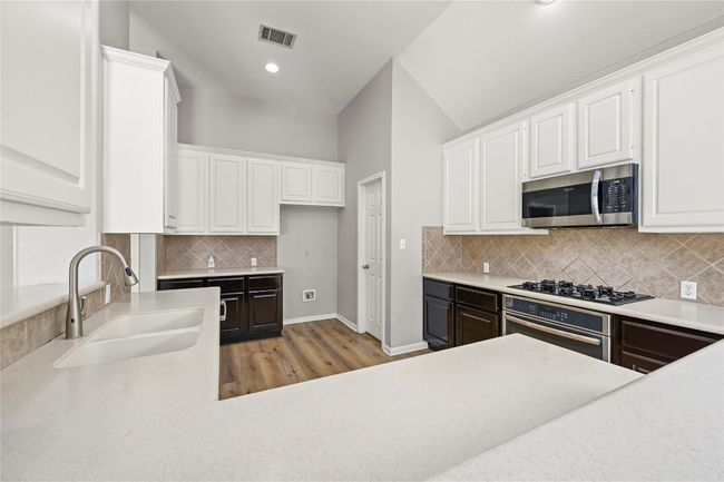 Kitchen with light wood-style flooring, appliances with stainless steel finishes, white cabinets | Image 10