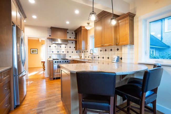 Kitchen featuring a breakfast bar area, a sink, a peninsula, light wood-style floors, and stainless steel appliances | Image 12