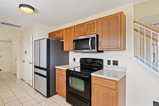 Kitchen with stainless steel appliances, light tile patterned floors, light countertops, and brown cabinets | Image 17