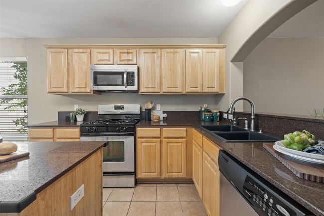 Kitchen featuring appliances with stainless steel finishes, light brown cabinets, a sink, and light tile patterned floors | Image 13