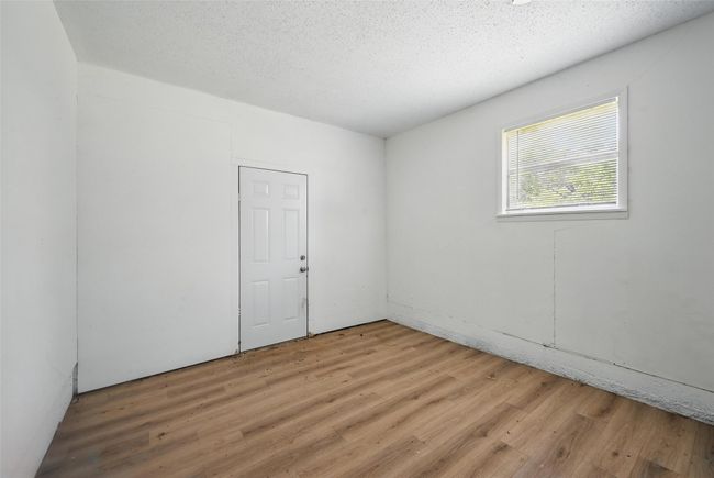 Empty room with light wood-type flooring and a textured ceiling | Image 11