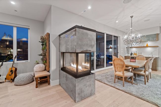 Dining room with wood finished floors, a high end fireplace, a chandelier, recessed lighting, and baseboards | Image 8