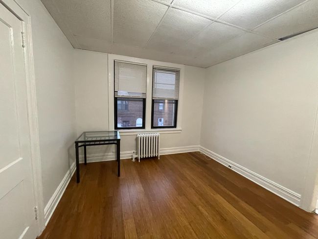 Spare room with radiator heating unit, dark wood-type flooring, and baseboards | Image 7