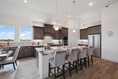 Kitchen with hardwood / wood-style flooring, custom range hood, stainless steel appliances, lofted ceiling, and an island with sink | Image 3