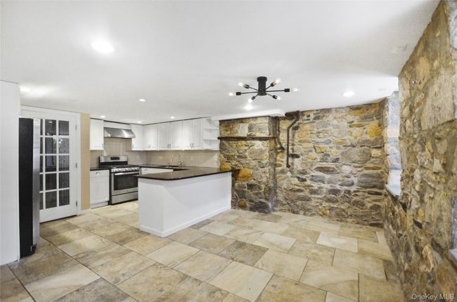 Kitchen featuring open shelves, stainless steel appliances, a chandelier, a peninsula, and white cabinets | Image 5