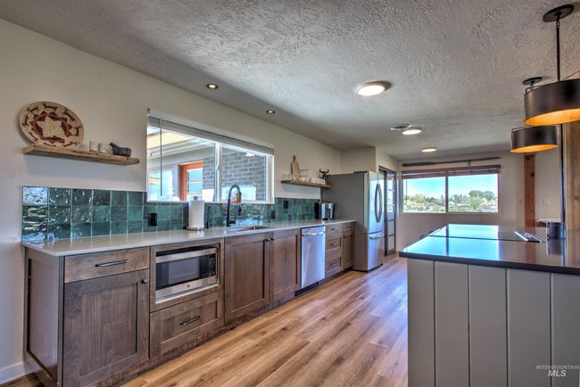 Kitchen with open shelves, stainless steel appliances, backsplash, light wood-style flooring, and a textured ceiling | Image 13