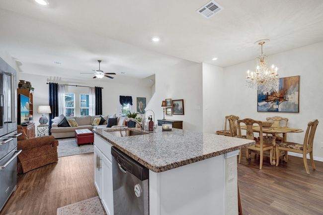 Kitchen featuring visible vents, white cabinets, dishwasher, a sink, and wood finished floors | Image 11