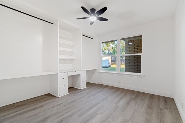 Unfurnished bedroom with ceiling fan, built in desk, and light hardwood / wood-style floors | Image 30