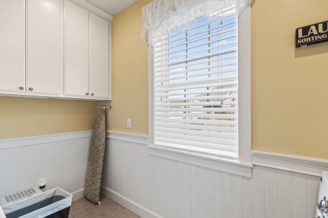 Laundry area featuring plenty of natural light, light tile patterned flooring, and cabinets | Image 53