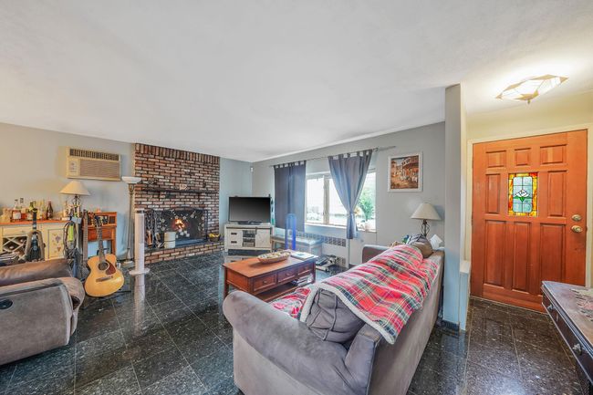 Living room featuring granite tiled floors and a brick fireplace. | Image 6