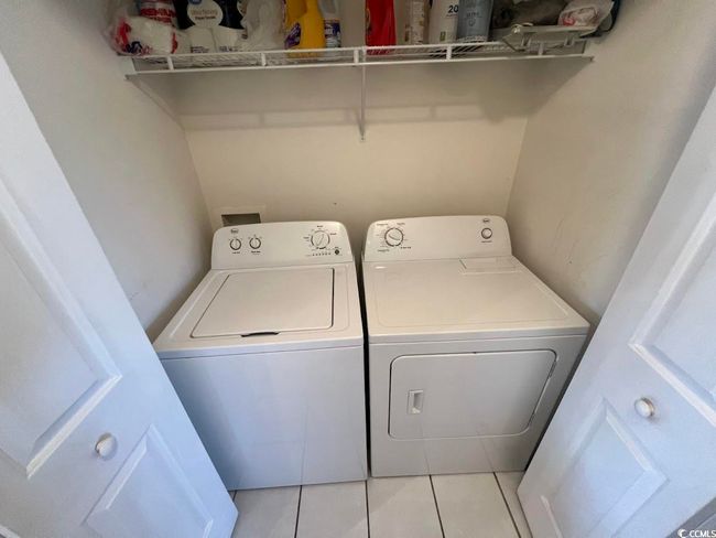 Laundry area with washing machine and clothes dryer and light tile patterned flooring | Image 10