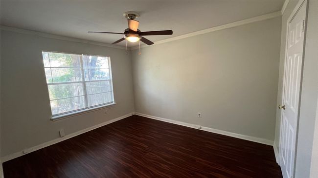 Empty room featuring dark wood-style floors, crown molding, baseboards, and ceiling fan | Image 9
