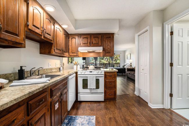 Kitchen with light countertops, white appliances, dark wood-style floors, and under cabinet range hood | Image 8