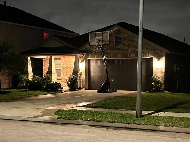 This home offers a beautifully lit front porch and yard, enhanced by a street lamp at the driveway's edge. | Image 4