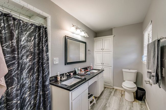 Full bath featuring a shower with curtain, baseboards, toilet, and vanity | Image 6