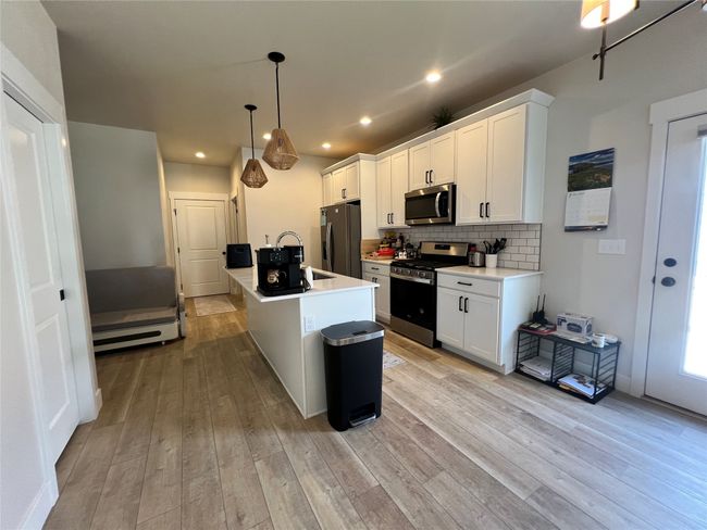 Kitchen with appliances with stainless steel finishes, a sink, light wood finished floors, white cabinetry, and recessed lighting | Image 12