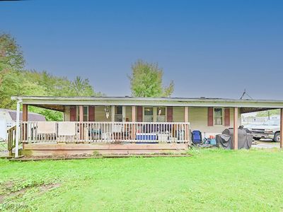 View of front of property with a front yard, a wooden deck, and a carport | Image 1