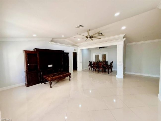 Living area with ornamental molding, ceiling fan, baseboards, visible vents, and lofted ceiling | Image 8