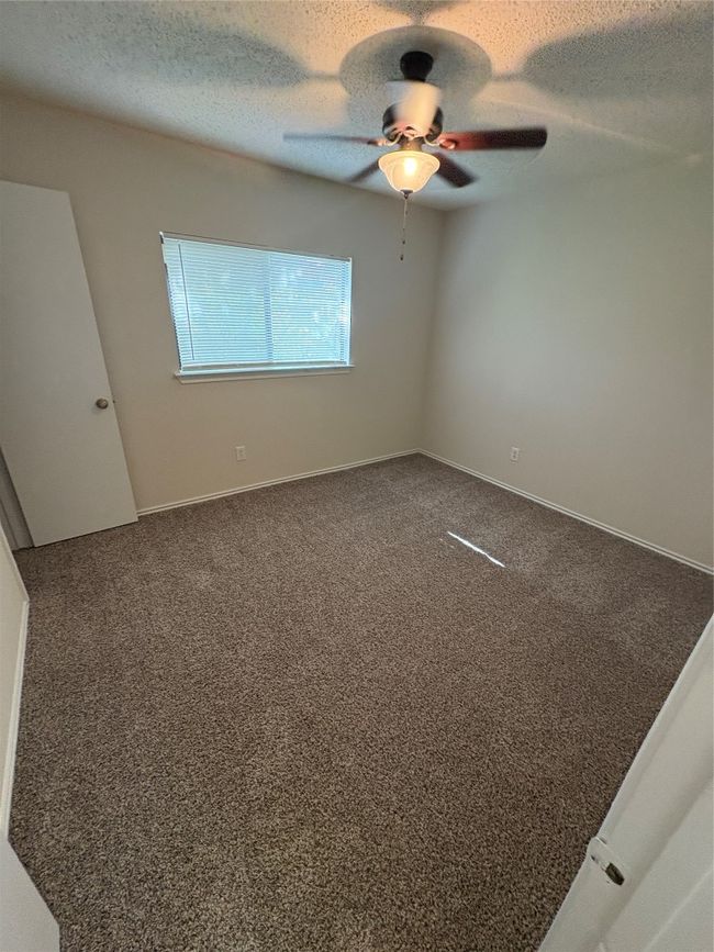 Unfurnished room featuring dark carpet, a textured ceiling, and ceiling fan | Image 16