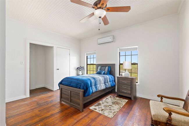 Bedroom with a wall mounted air conditioner, ornamental molding, dark wood-type flooring, and ceiling fan | Image 18