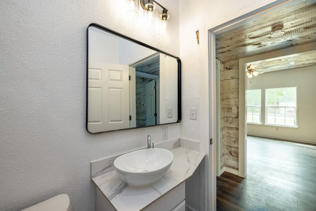 Bathroom with a textured wall, toilet, vanity, and wood finished floors | Image 21