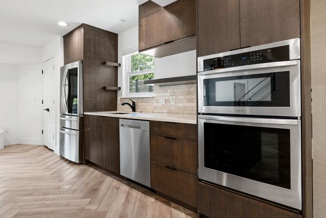 Kitchen with open shelves, light countertops, a sink, dark brown cabinetry, and appliances with stainless steel finishes | Image 16