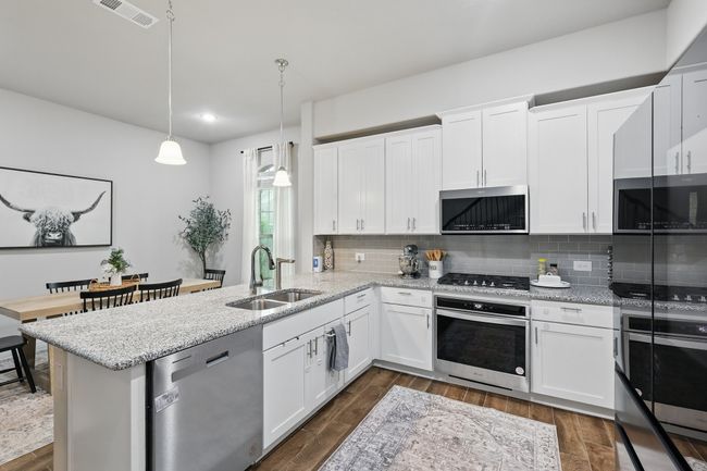 Kitchen featuring a sink, a peninsula, visible vents, backsplash, and appliances with stainless steel finishes | Image 4