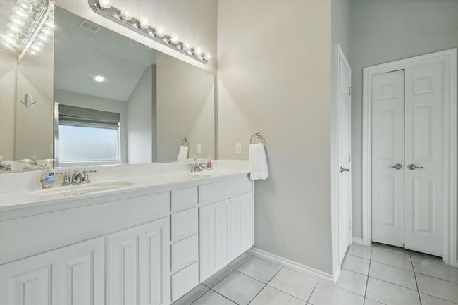 Full bathroom with double vanity, visible vents, tile patterned flooring, a sink, and a closet | Image 24