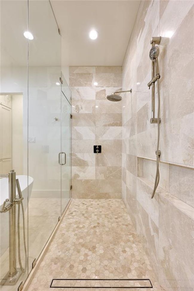 Spacious walk-in shower adorned with limestone and marble mosaic tile, creating a luxurious and visually striking design. | Image 32