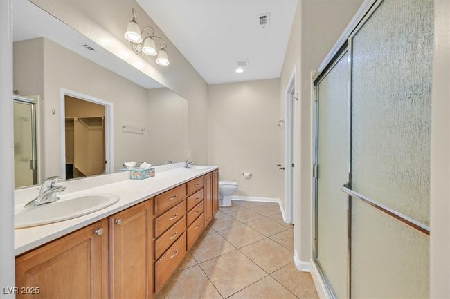 Primary bathroom with a walk-in closet, dual vanities, walk-in shower, and tile patterned floors | Image 14