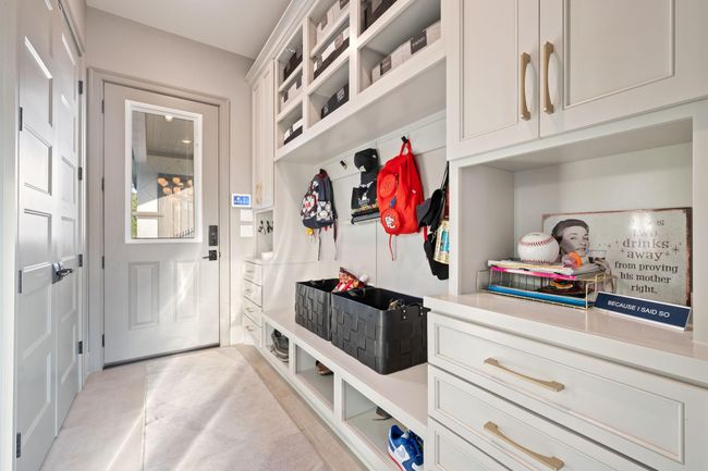 A well-organized mudroom with built-in storage, including shelves, drawers, and hooks for hanging items. The space is bright, with a door leading outside and stylish cabinetry, providing functional and attractive storage solutions. | Image 23