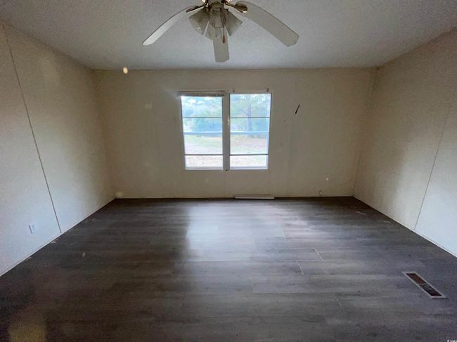 Empty room featuring visible vents, ceiling fan, and dark wood-style floors | Image 19
