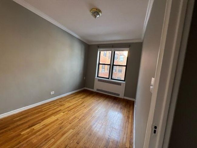 Spare room featuring light wood-style flooring, baseboards, ornamental molding, and radiator heating unit | Image 8