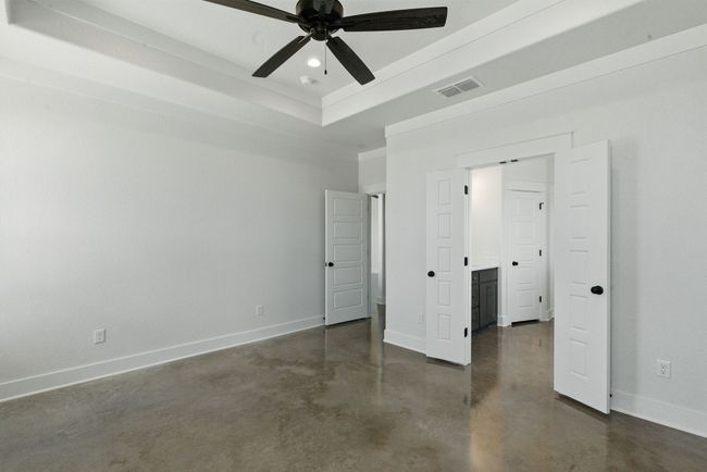 Unfurnished bedroom with finished concrete floors, baseboards, a raised ceiling, crown molding, and recessed lighting | Image 10