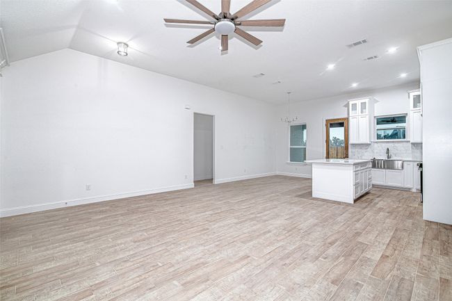Kitchen with open floor plan, light countertops, a chandelier, a sink, and light wood finished floors | Image 4