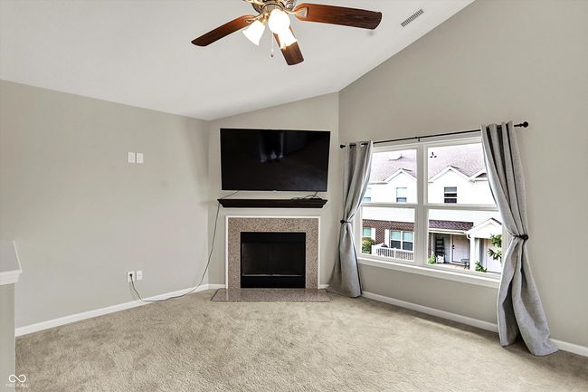 unfurnished living room featuring vaulted ceiling, light carpet, a fireplace with flush hearth, and ceiling fan | Image 10