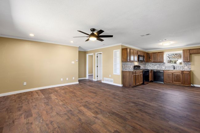 Kitchen with visible vents, decorative backsplash, dark wood-style floors, open floor plan, and black appliances | Image 10