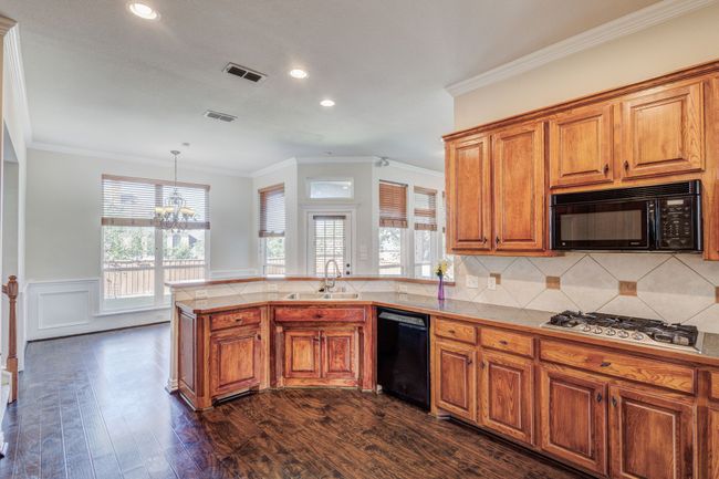 Kitchen with backsplash, decorative light fixtures, a chandelier, black appliances, and sink | Image 25