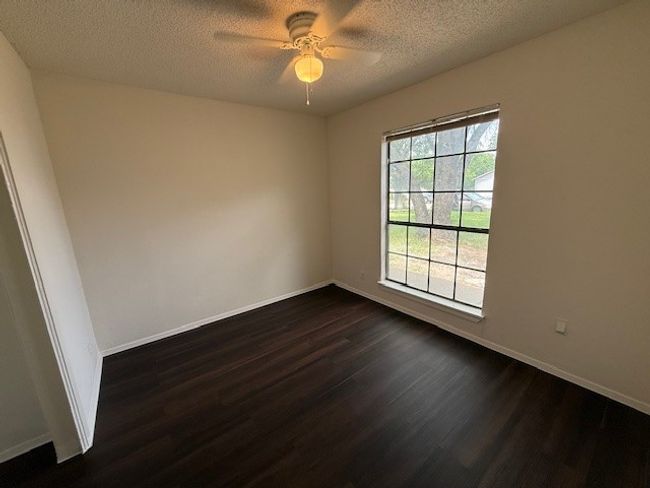Unfurnished room featuring dark wood-style floors, a ceiling fan, baseboards, and a textured ceiling | Image 11