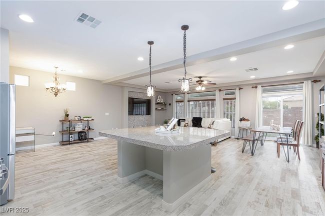 Kitchen featuring visible vents, light wood finished floors, pendant lighting, and ceiling fan with notable chandelier | Image 16