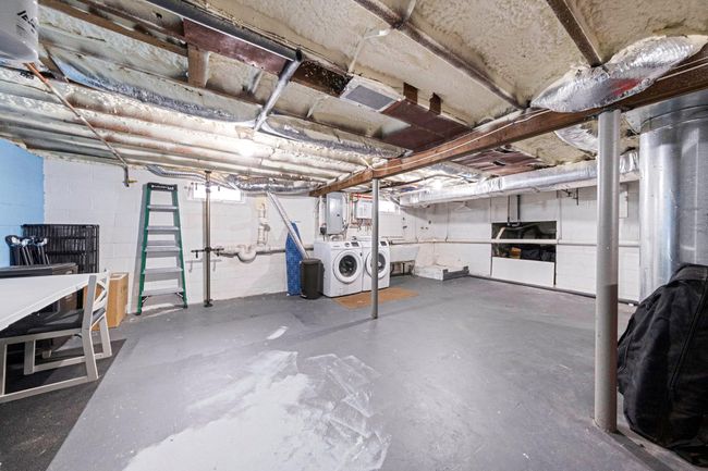 Unfinished below grade area with washing machine and clothes dryer, electric panel, a sink, and concrete block wall | Image 38