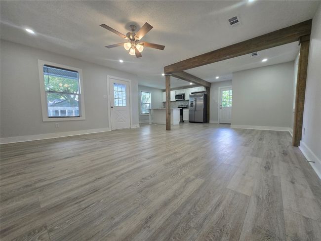 Unfurnished living room with ceiling fan, light wood-style flooring, recessed lighting, and beamed ceiling | Image 6